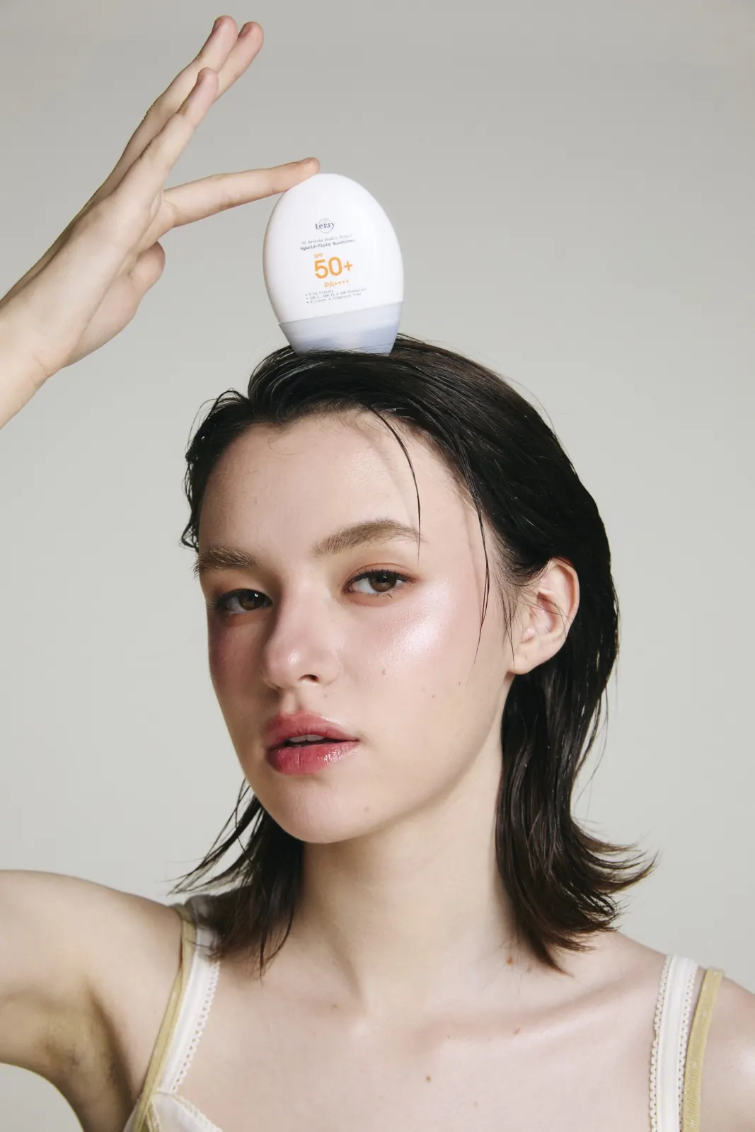 นางแบบทูนขวด UV Defense ไว้บนศีรษะ ยกมือประคองไว้ทั้งสองข้าง