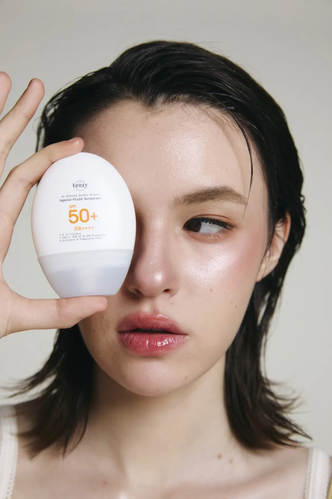 นางแบบถือขวด UV Defense บังดวงตาข้างหนึ่ง เห็นฉลาก SPF50+ เต็มขวด